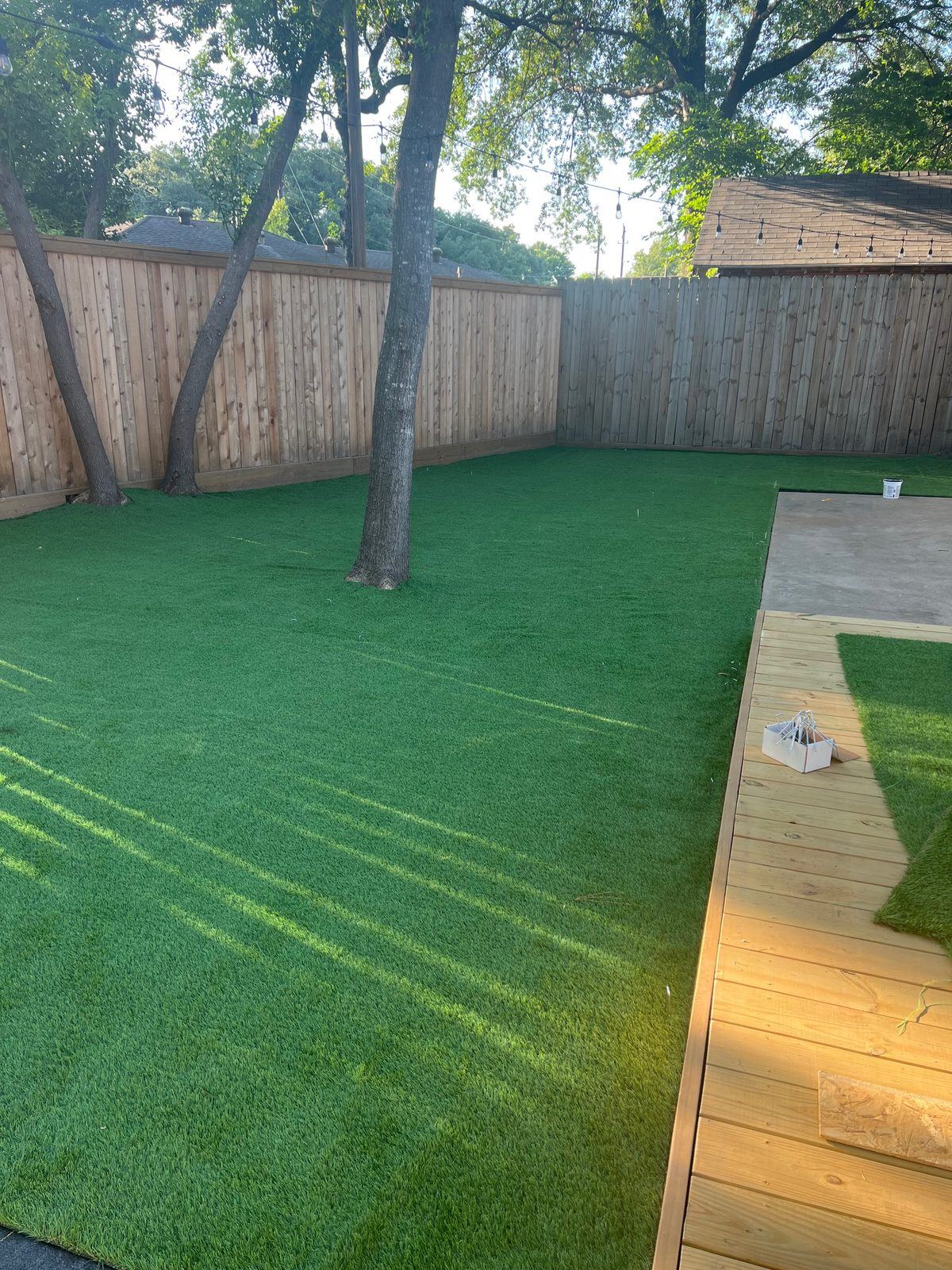 Lush finished turf under mature trees beside a new deck