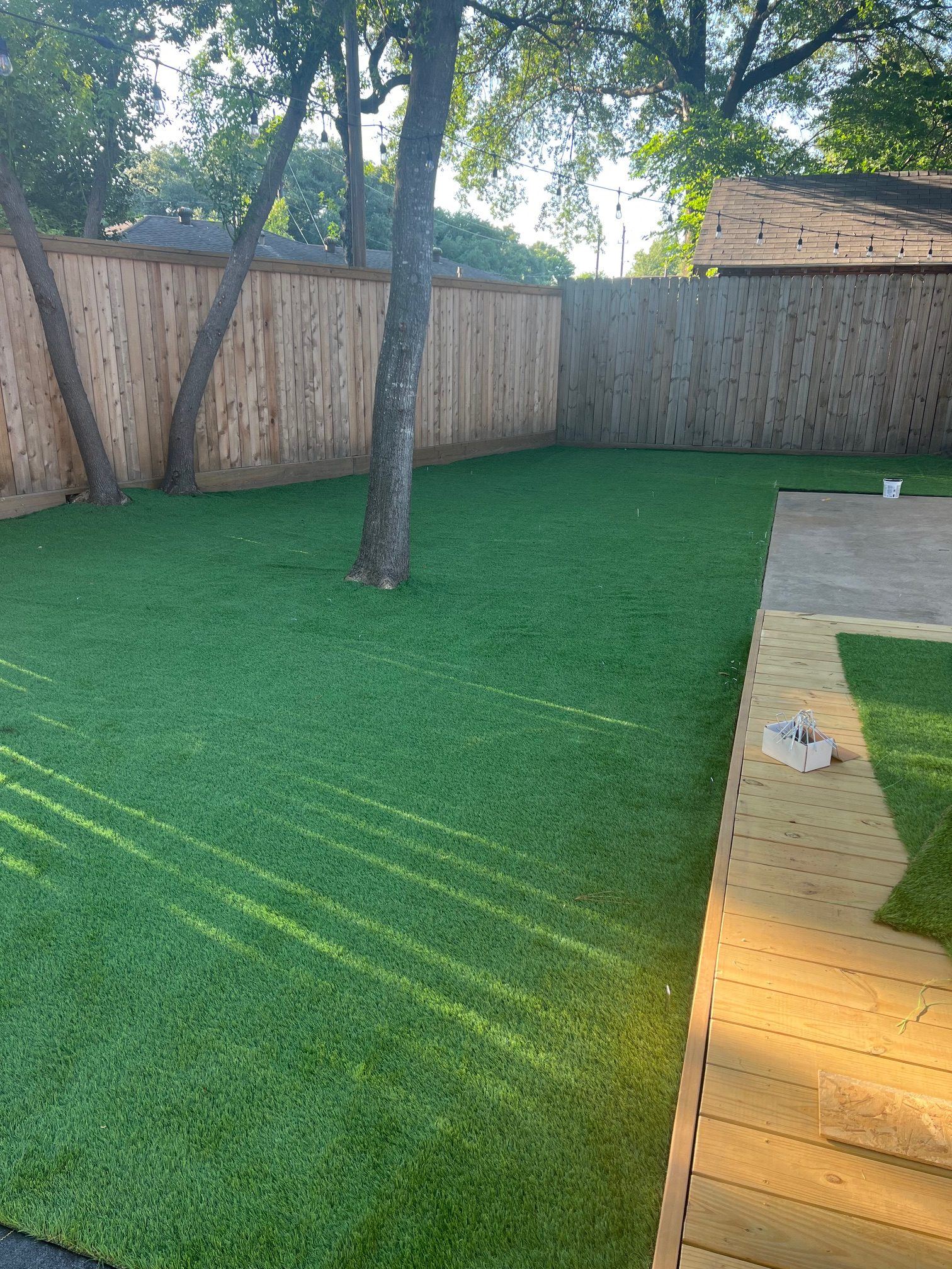 Lush Monarch artificial turf installation under mature trees with a new wooden deck