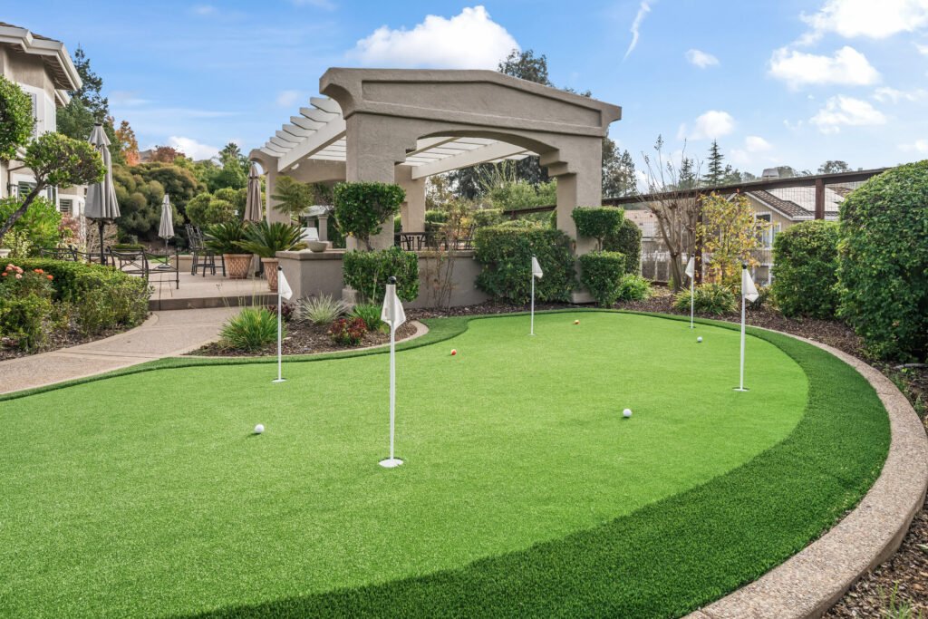 Custom residential putting green installed by Monarch — multi-cup green with real flags and landscaping