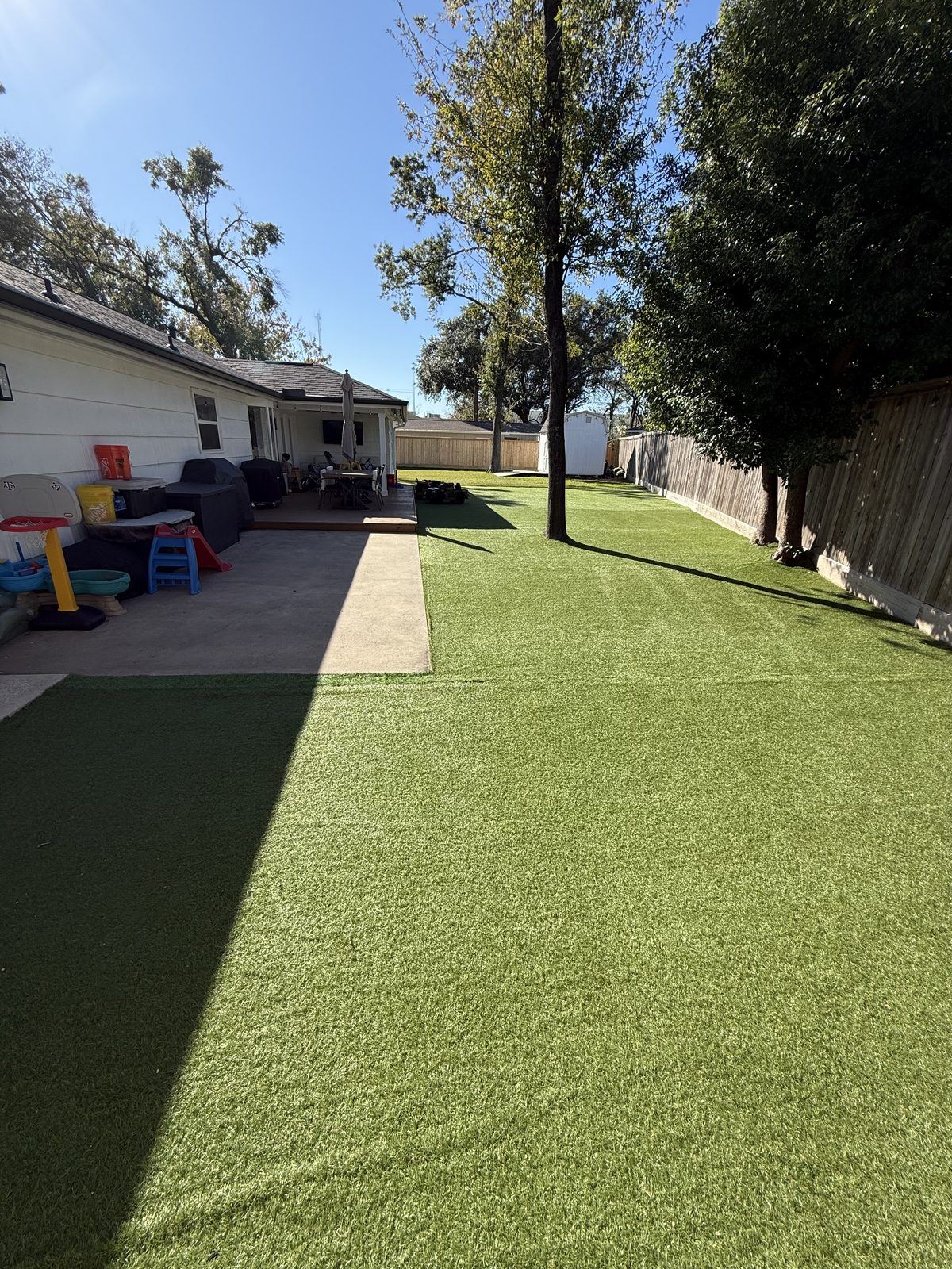 Side-yard turf installation extending from a covered patio
